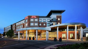 Ein Hampton Inn & Suites Hotel mit modernem Design, das eine Ziegel-Fassade und einen geschwungenen Eingang zeigt.