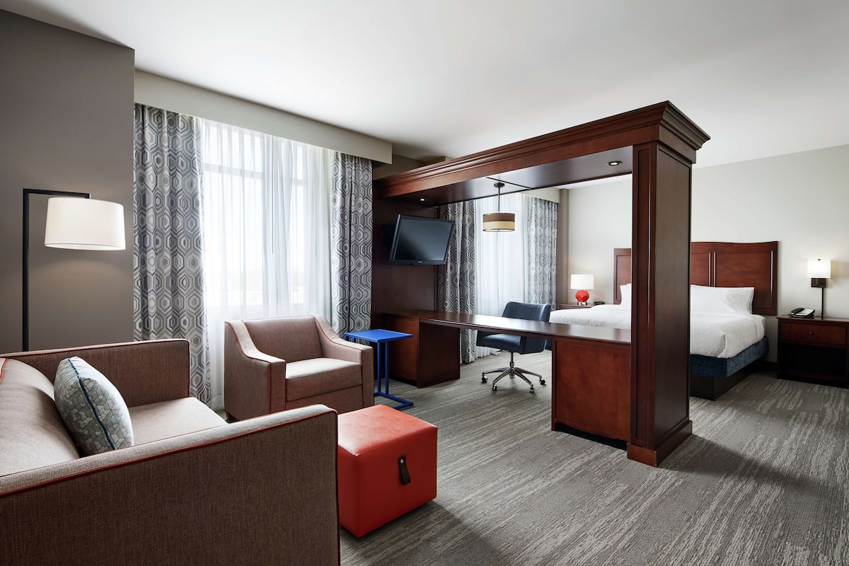 A hotel room with a sofa, armchair, desk, and bed.