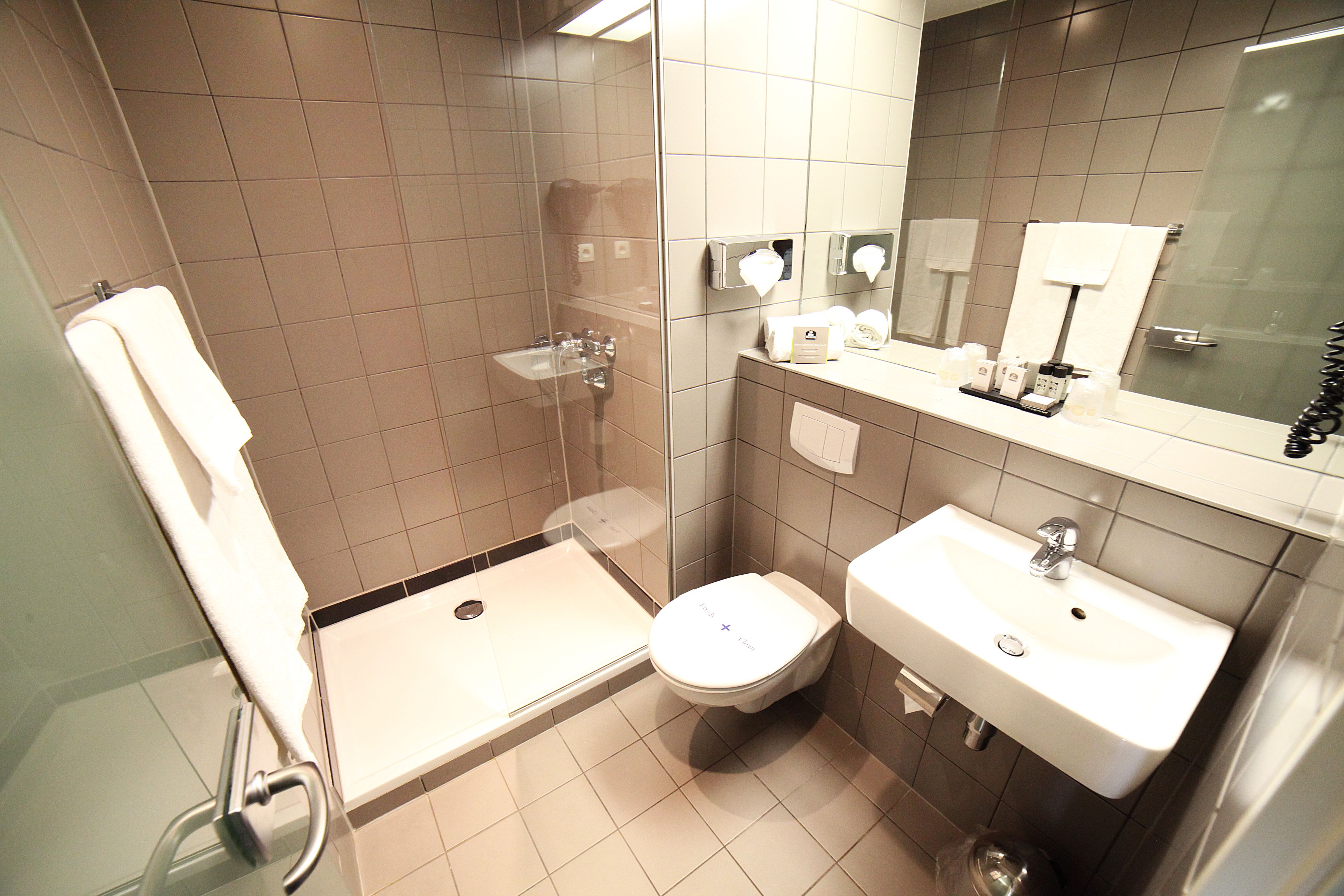 A modern bathroom with a shower, toilet, and sink.