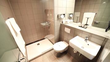 A modern bathroom with a shower, toilet, and sink.