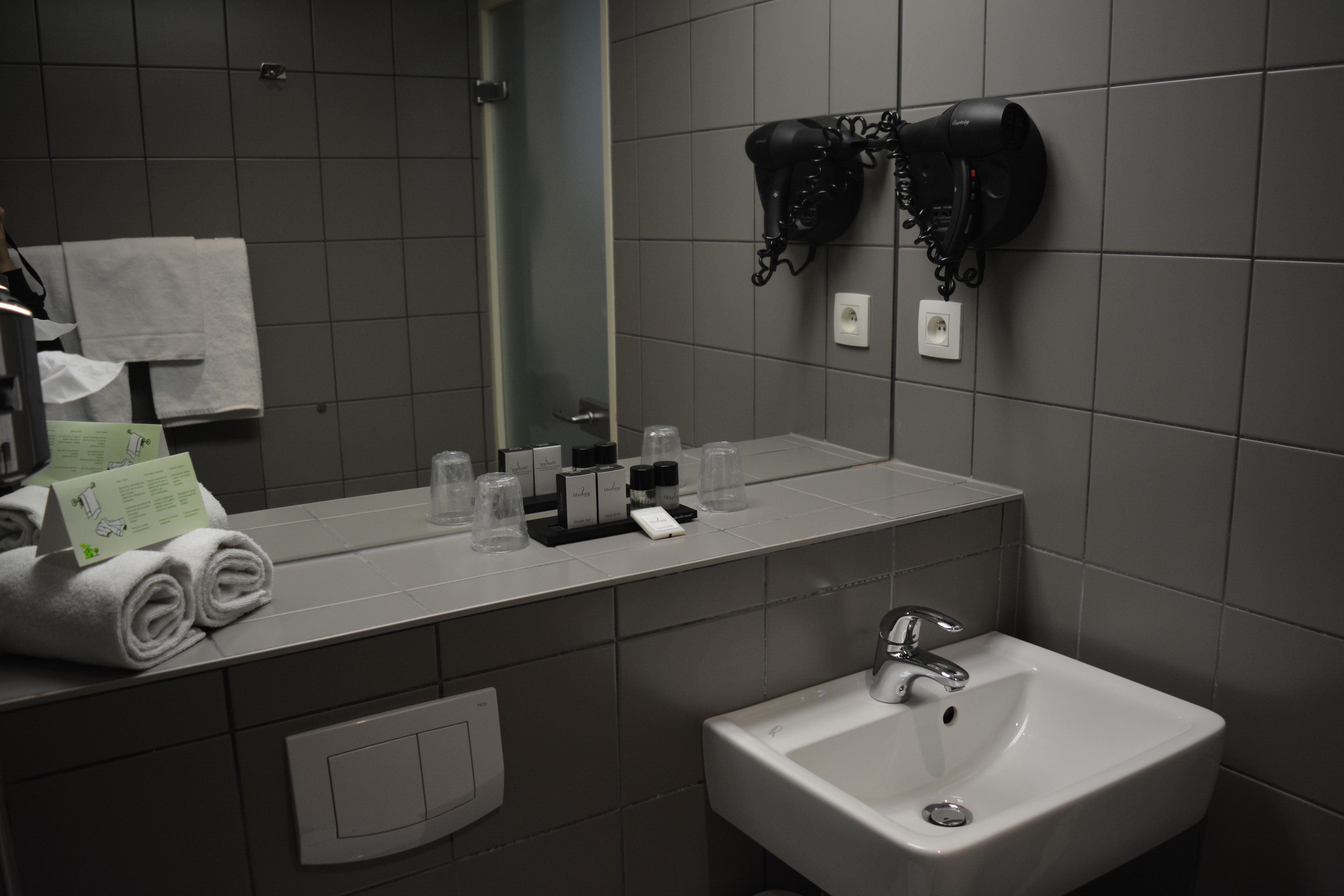 A bathroom with a sink, mirror, towel rack, and hairdryer.