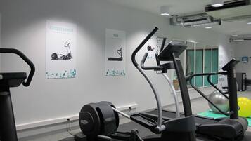 Une salle de sport équipée de tapis de course, de vélos elliptiques et d’un vélo d’appartement.