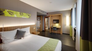 A hotel room with a large bed, a desk, a TV, and a bathroom visible through an open door. - Best Western Hotel Brussels South (Sint-Pieters-Leeuw)