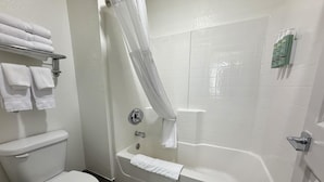 A bathroom with a toilet, a bathtub, and a shower curtain.