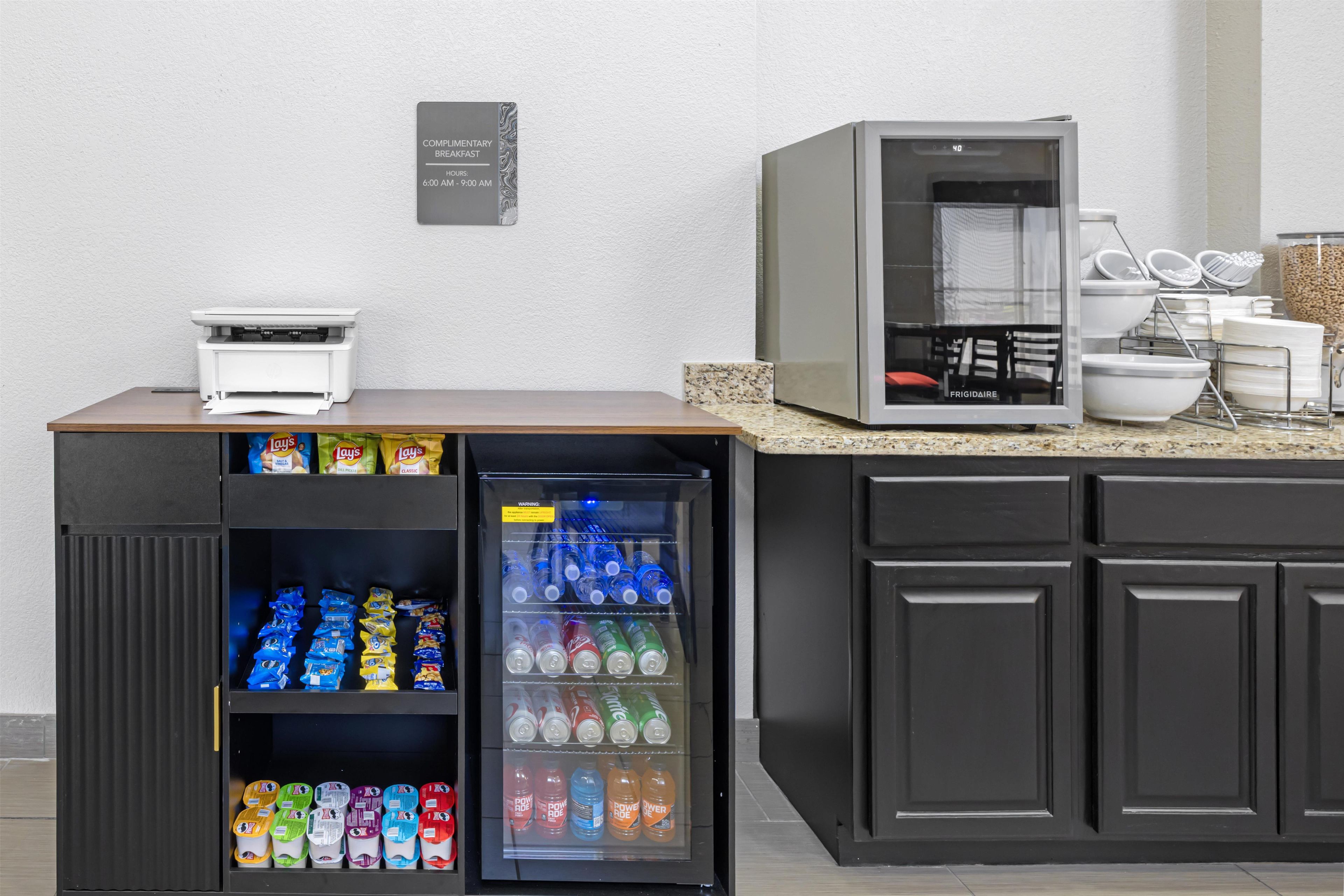 Una kitchenette con refrigerador lleno de bebidas, microondas y cafetera.
