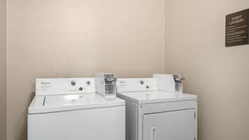 Un lavadero de hotel con dos lavadoras y secadoras Whirlpool, un letrero para huéspedes y las instrucciones de uso.