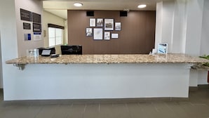 A reception desk with a check-in counter, a computer, and a wall with framed pictures and signs.