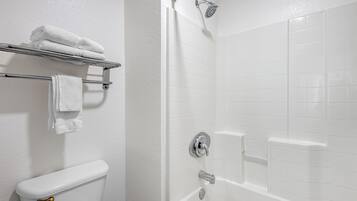 Un baño con inodoro, un perchero con toallas dobladas, una ducha con cabezal de ducha de mano y una bañera con grifo.
