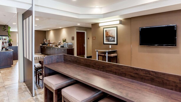 A modern hotel lobby with a long reception desk, seating area, and a flat-screen TV mounted on the wall. - Microtel Inn & Suites by Wyndham Wheeler Ridge (Arvin)