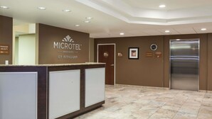 A reception area with a counter, a clock, and an elevator. - Microtel Inn & Suites by Wyndham Wheeler Ridge (Arvin)