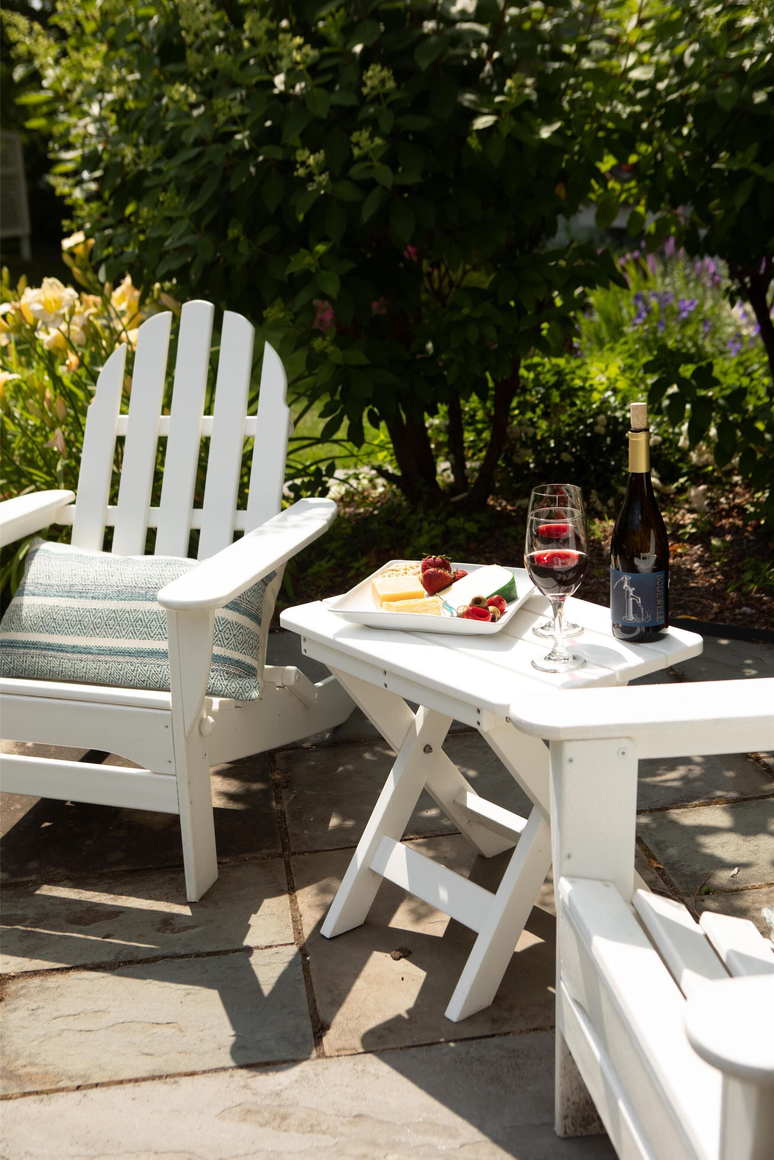 Zona relax esterna con tavolo, una bottiglia di vino e un piatto di fragole e formaggio.