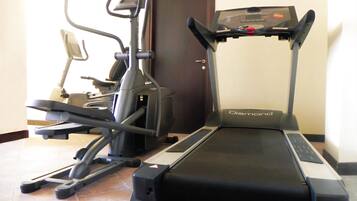 A treadmill and elliptical machine in a room with a tiled floor and a wooden door.