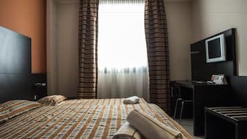 Une chambre d’hôtel équipée d’un lit, d’un bureau, d’une chaise et d’un téléviseur.