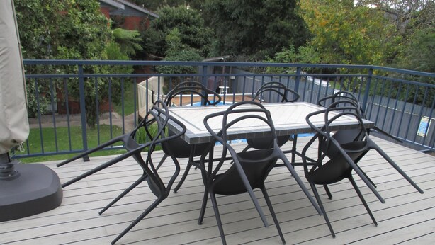 A deck with a table and chairs, surrounded by a blue railing. - Harbour Lights Holiday Units (Merimbula)