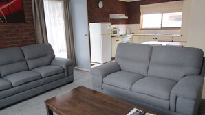 A living room with two grey sofas and a wooden coffee table. - Harbour Lights Holiday Units (Merimbula)