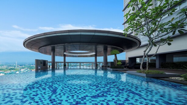 Ein Swimmingpool mit Schachbrettmuster, umgeben von einem modernen Gebäude mit einer gewölbten Dachkonstruktion.