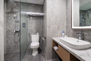 Une salle de bain moderne avec une douche à parois de verre, des toilettes blanches et un meuble-lavabo recouvert de carreaux de marbre avec un évier.