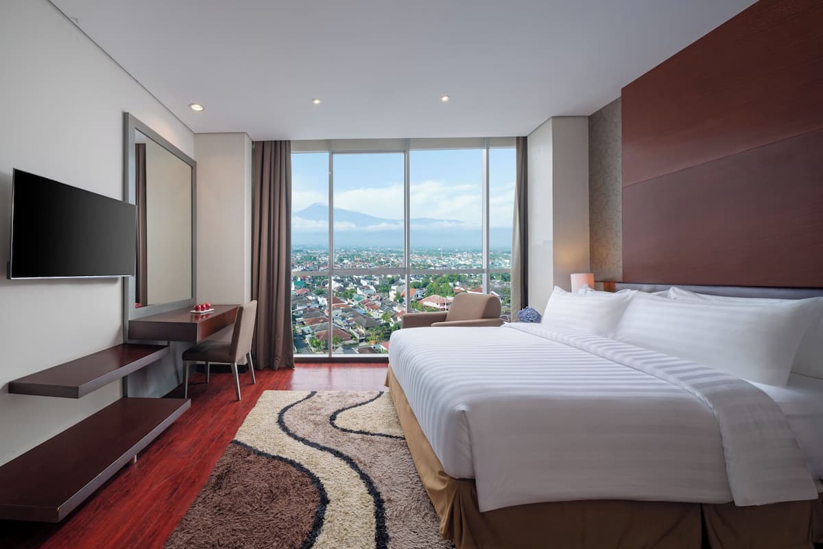 Een moderne hotelkamer met een groot bed, een bureau en een televisie.