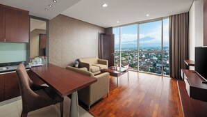 Ein modernes Hotelzimmer mit Essbereich, einer Couch und einem großen Fenster mit Blick auf die Stadt.