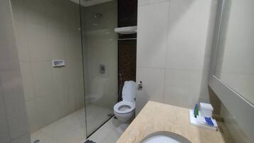 Une salle de bain moderne dotée d’une douche à parois de verre, de toilettes et d’un lavabo avec un plan de travail en marbre.