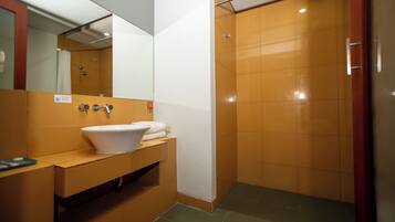 A modern bathroom with a white sink, a mirror, and a shower area.