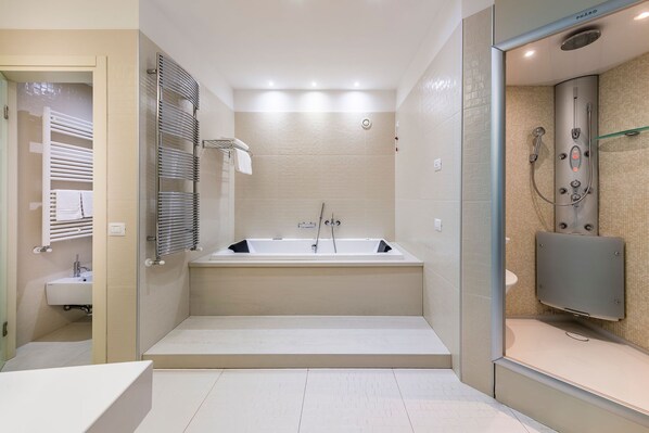 Un baño moderno con una bañera grande, zona de ducha separada y tocador con lavabo.