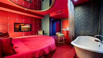 Quarto com uma cama grande, banheira e televisão na parede.
