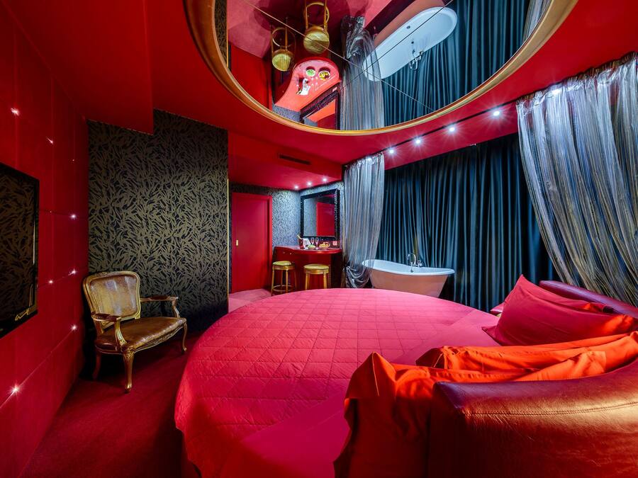 Une chambre à coucher luxueuse avec un grand lit, une coiffeuse avec un miroir et une baignoire.