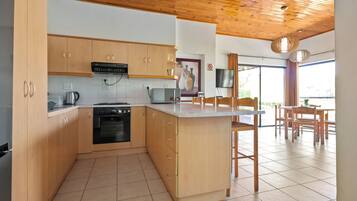 Una cocina moderna con armarios de madera, horno empotrado y una isla grande con taburetes de bar.