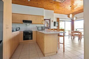 Una cocina moderna con armarios de madera, horno empotrado y una isla grande con taburetes de bar.