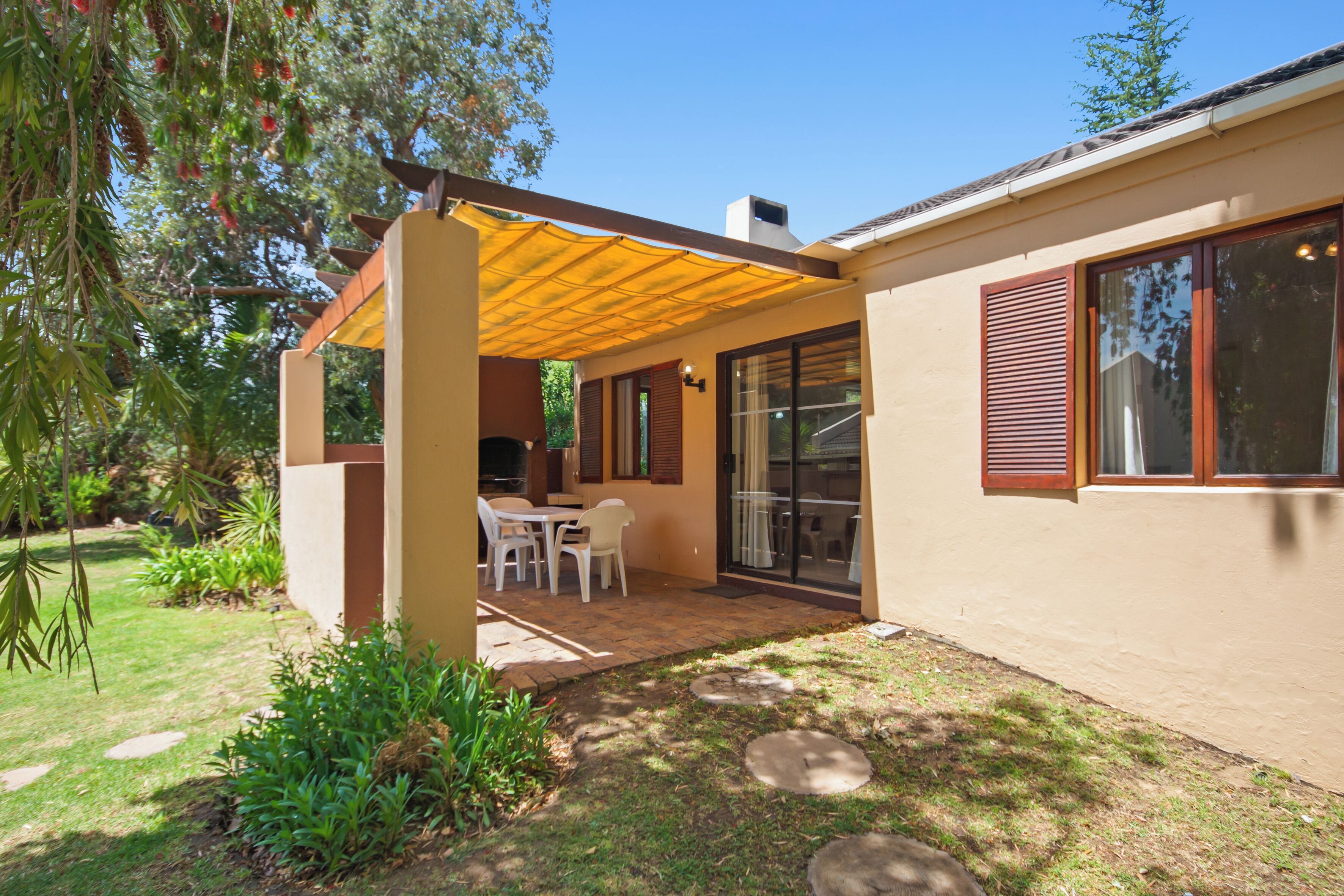 A house with a covered patio, a dining area, and a garden.