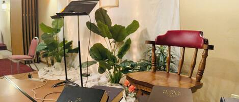Une pièce comprenant une table où sont exposés plusieurs exemplaires de la Bible, un pied de micro et une chaise.