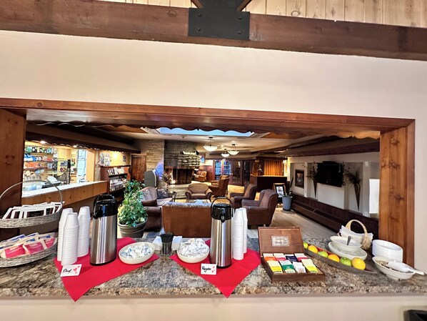 A cozy lobby with a stone fireplace, comfortable seating, and a coffee station with disposable cups and a thermos. - Lodge at Leathem Smith (Sturgeon Bay)