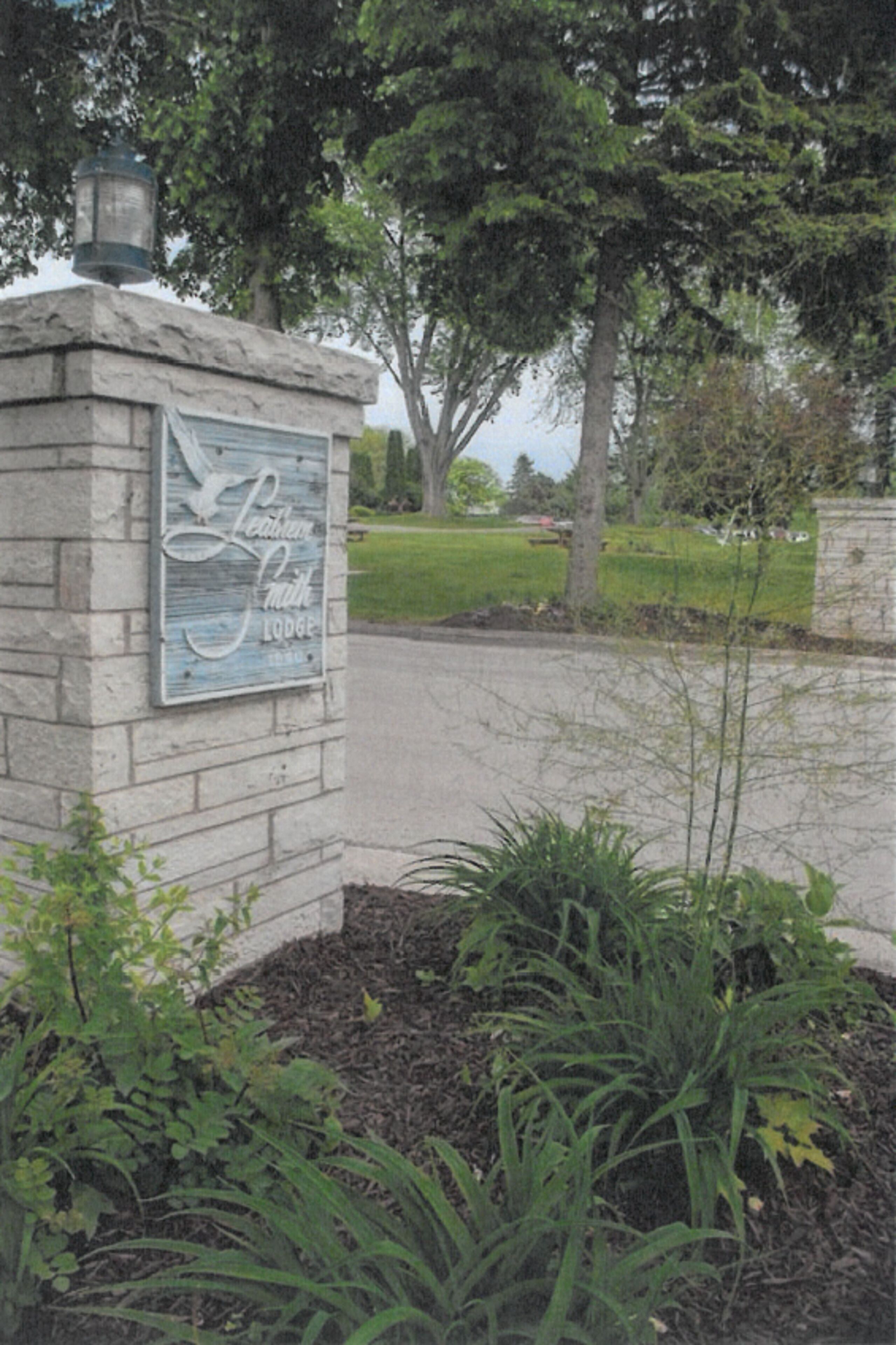 A stone sign with the text "Leather Smith Lodge" and a lamp on top.