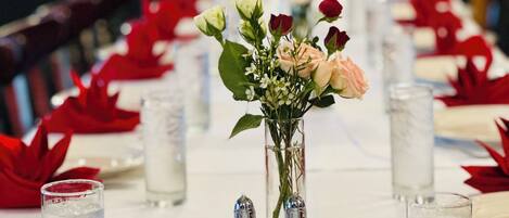Ein langer Esstisch mit floralen Tischdekorationen, Salz- und Pfefferstreuern und Gläsern mit Wasser.