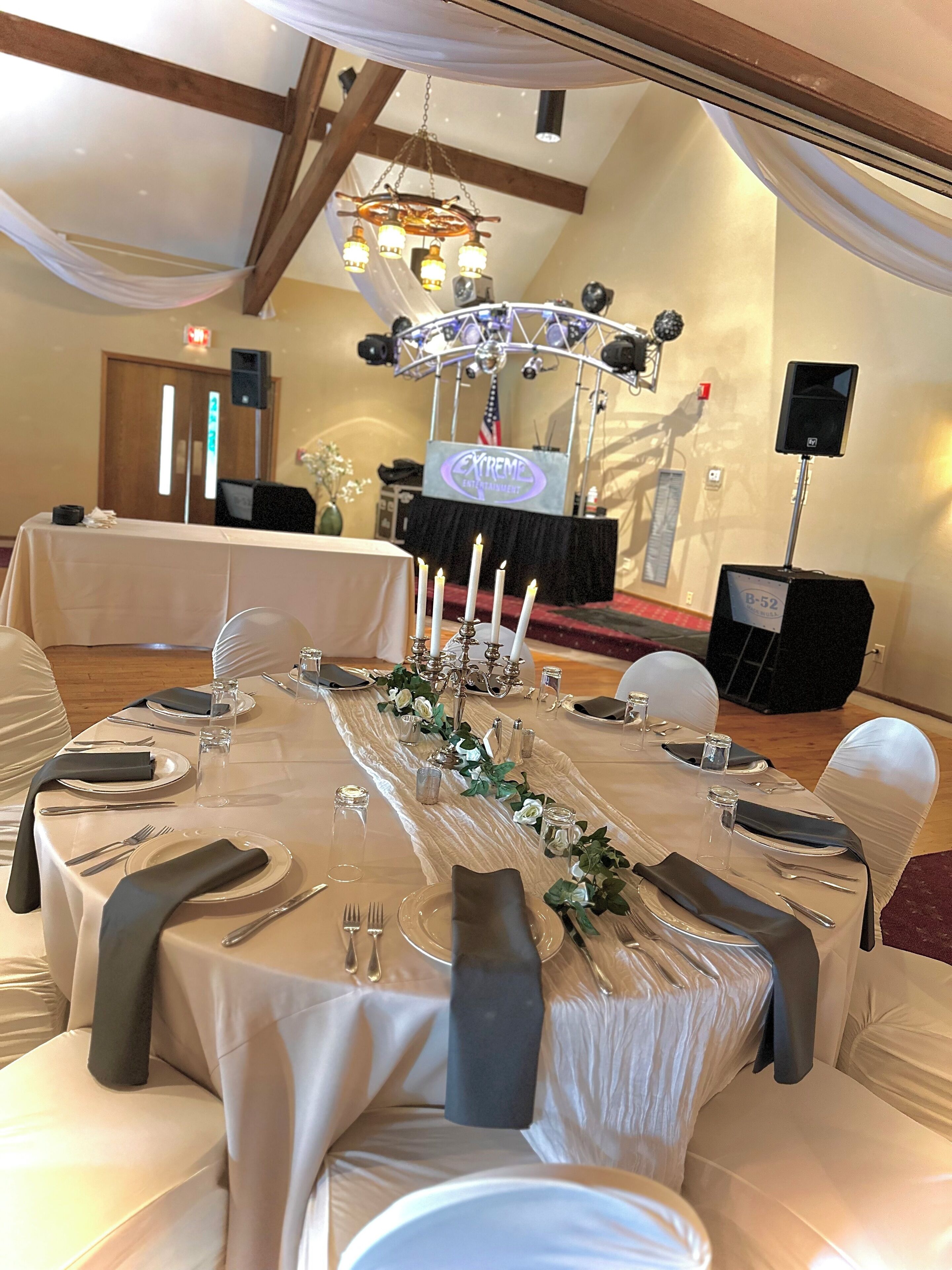 A banquet table set for a formal event with white tablecloths, silverware, and candles.