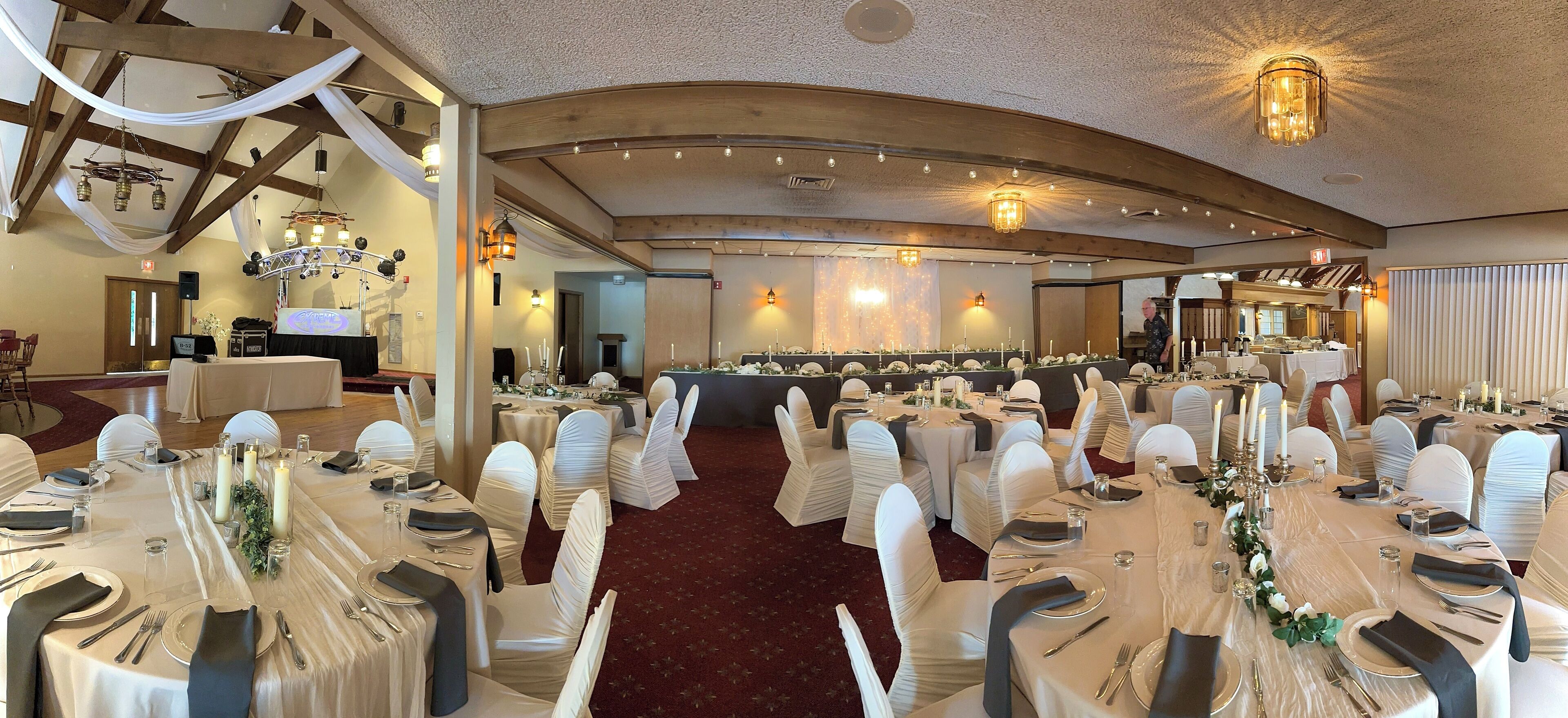 A banquet hall with round tables, white tablecloths, and chairs with white sashes.