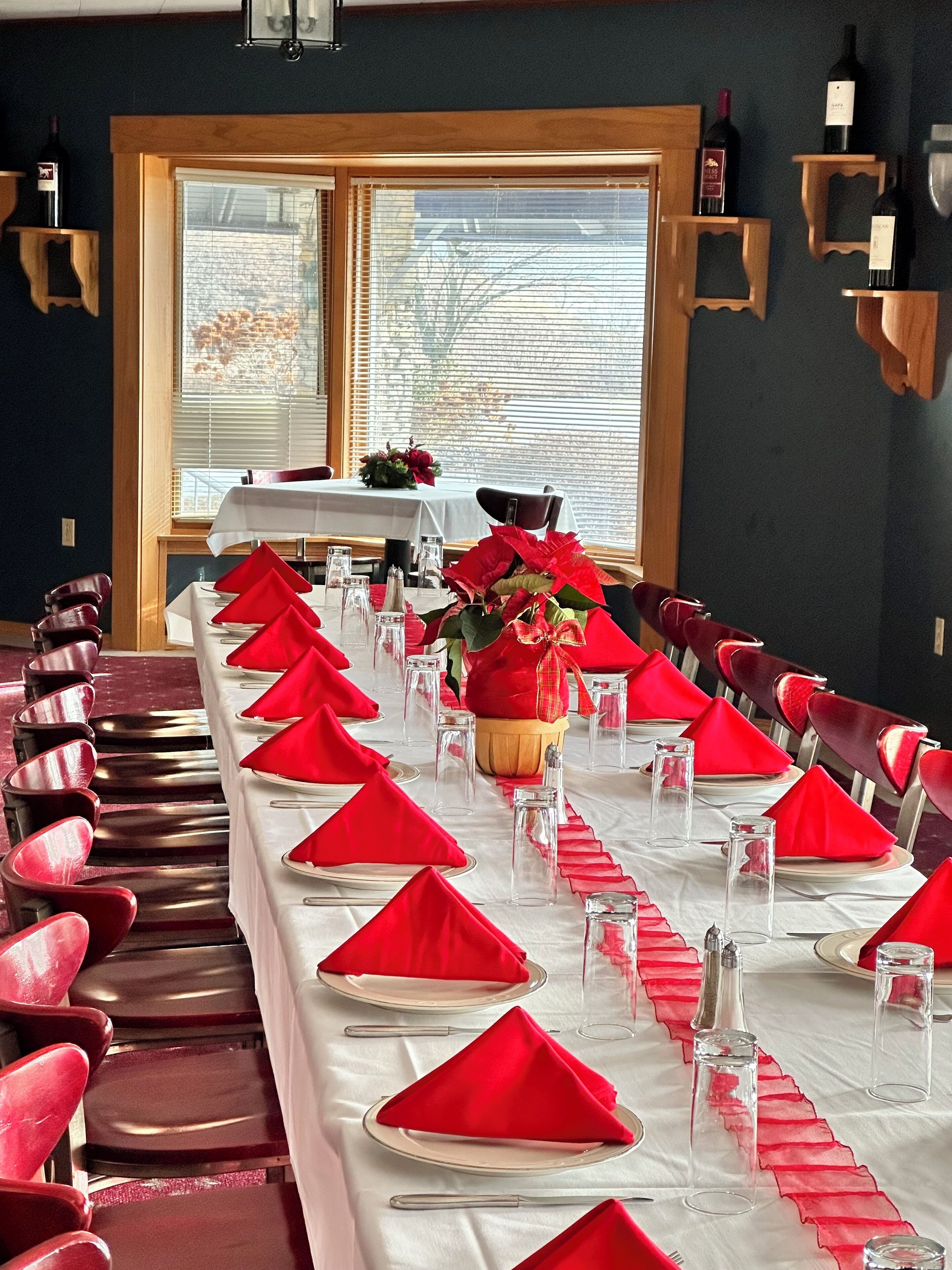 A long dining table set with red napkins, clear glasses, and a centerpiece.