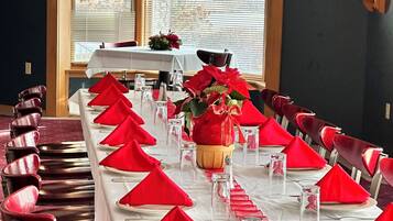 A long dining table set with red napkins, clear glasses, and a centerpiece.