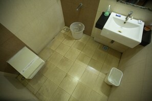 Un baño pequeño con un lavamanos blanco, un inodoro y un cubo de basura.