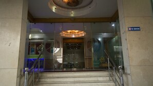 A hotel entrance with a glass facade, a "NO SMOKING" sign, and a modern ceiling light fixture. - Mahalaya Residency (Chennai)