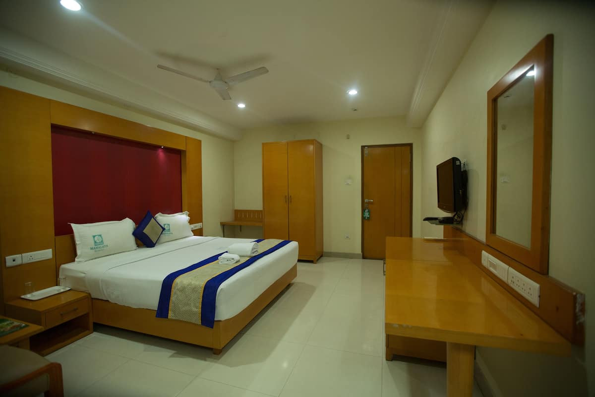 Habitació d'hotel amb llit, taulell de nit, armari i televisió.