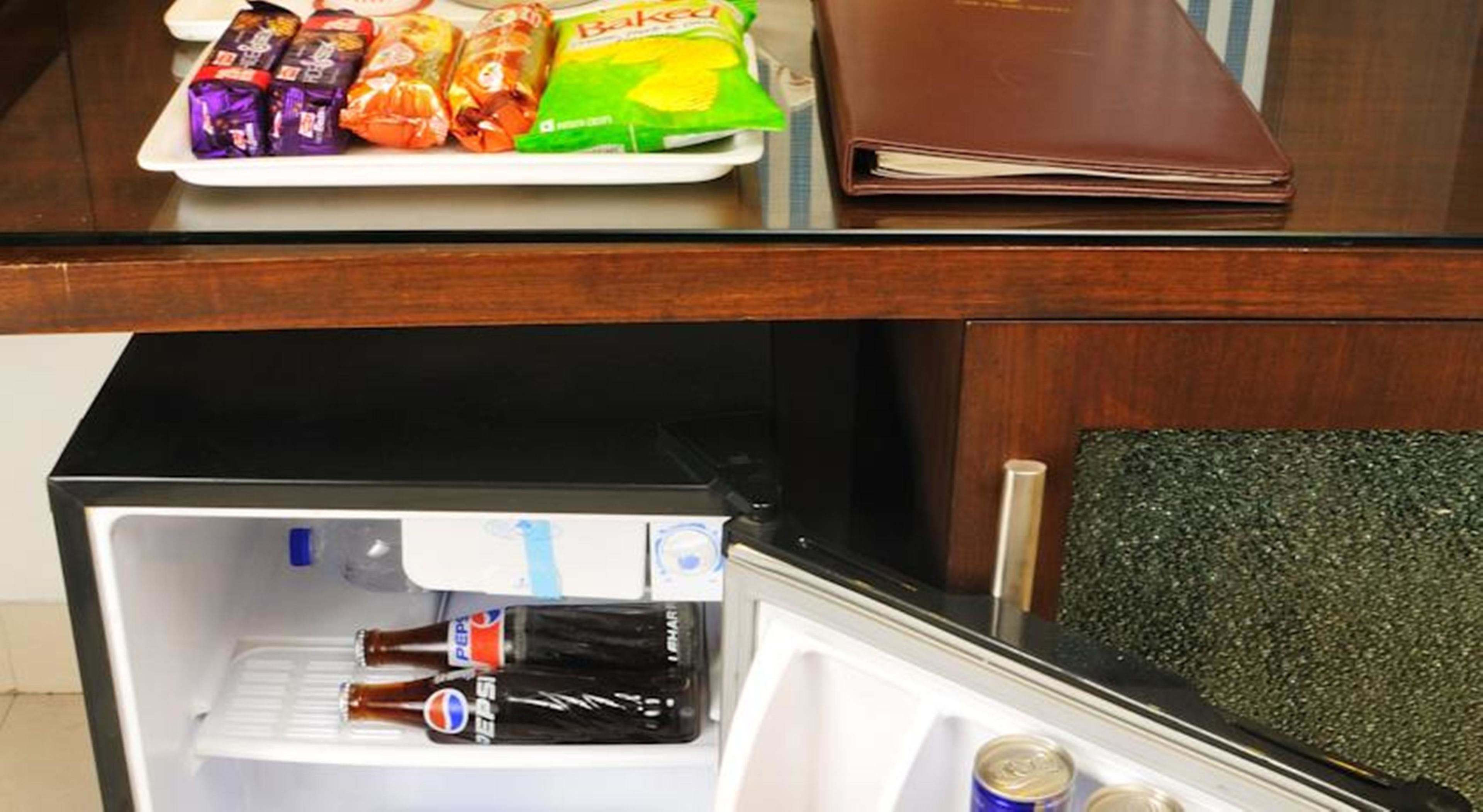 A kitchen counter with a plate of snacks, a brown wallet, and a refrigerator containing beverages and cans.