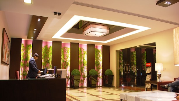 A hotel lobby with a reception desk, a seating area, and a large mirror.