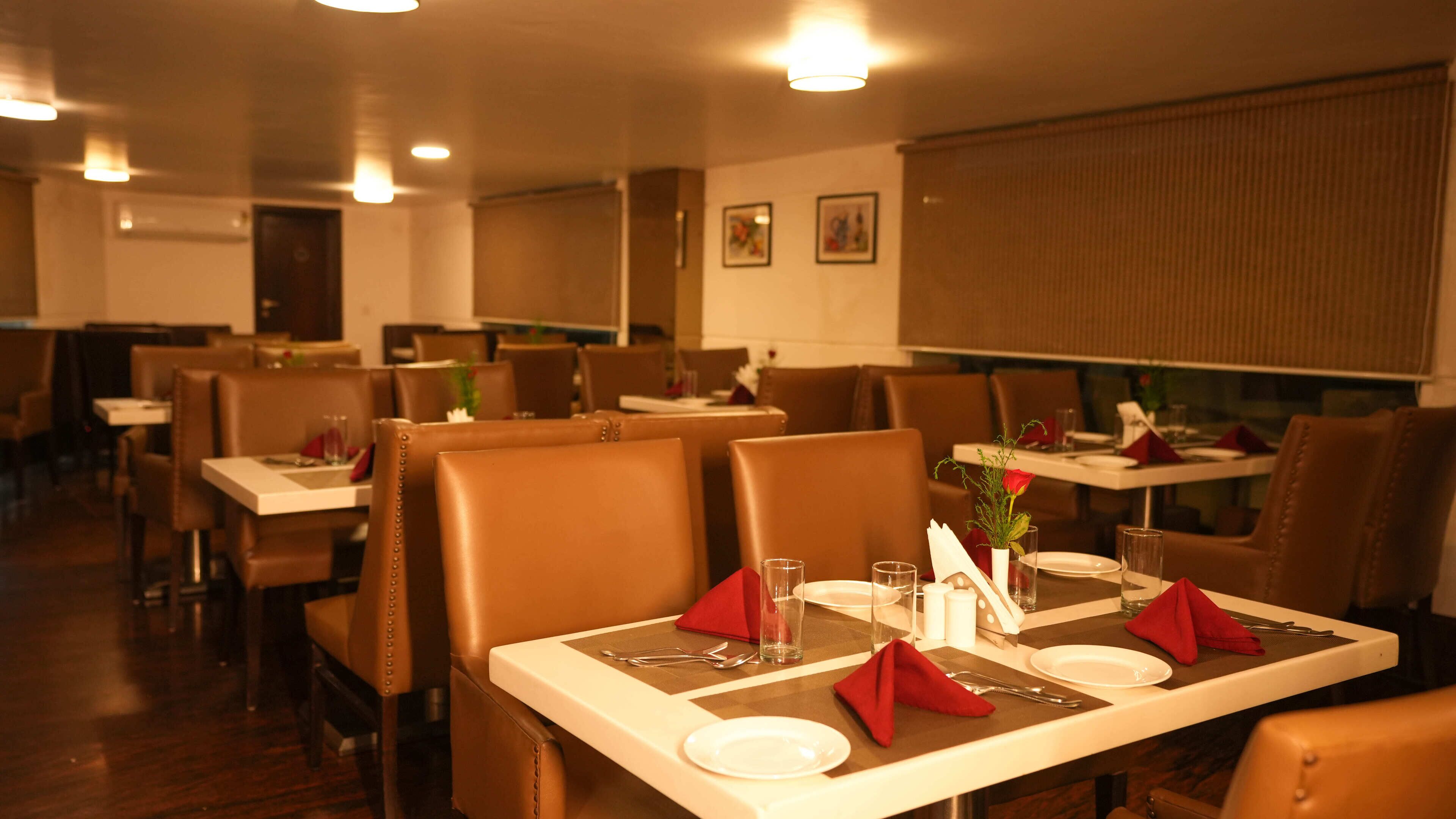 Een restaurant met zitjes en tafels, elk voorzien van bestek, servetten en glazen.