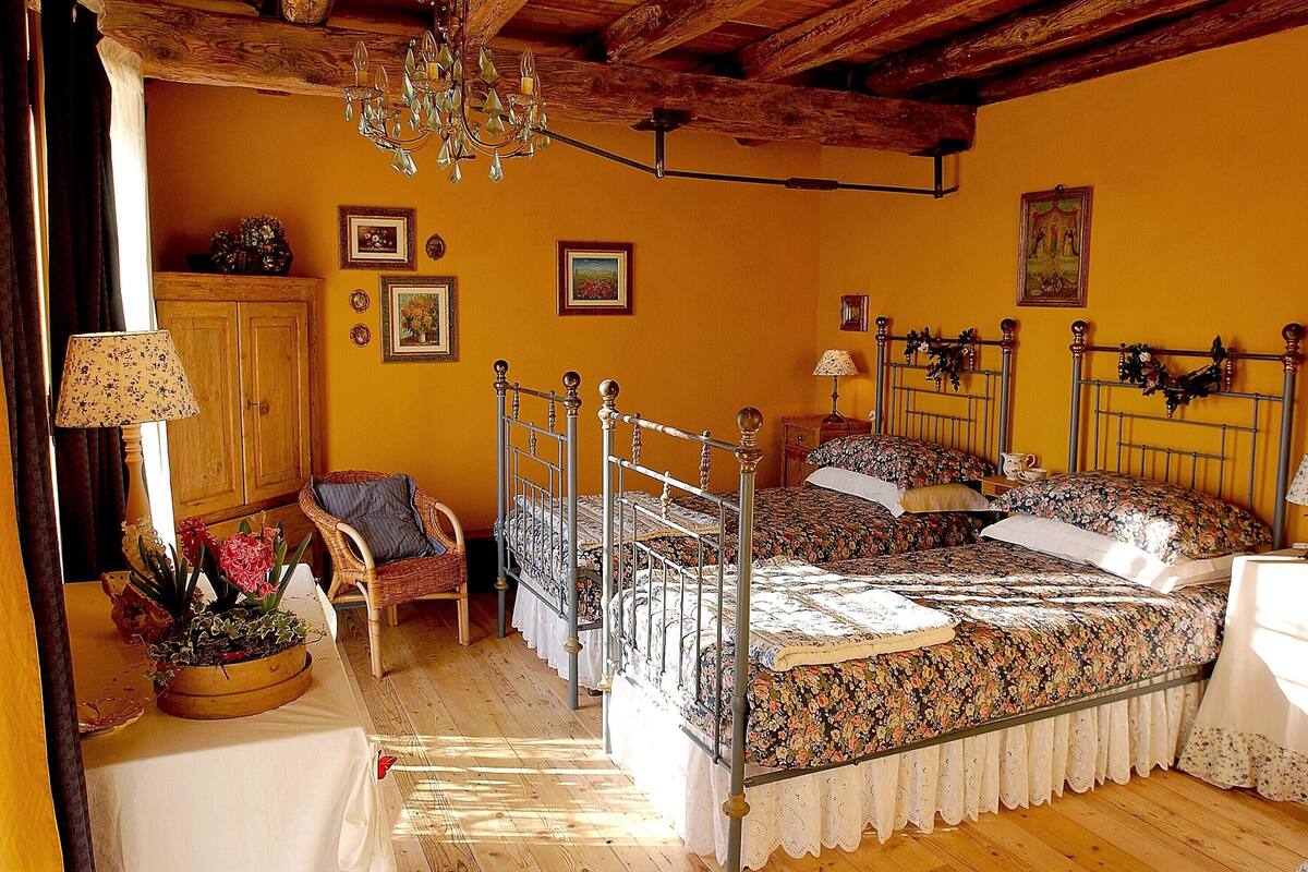 Un dormitorio con una cama, dos mesitas de noche, una silla, un armario de madera y un candelabro.