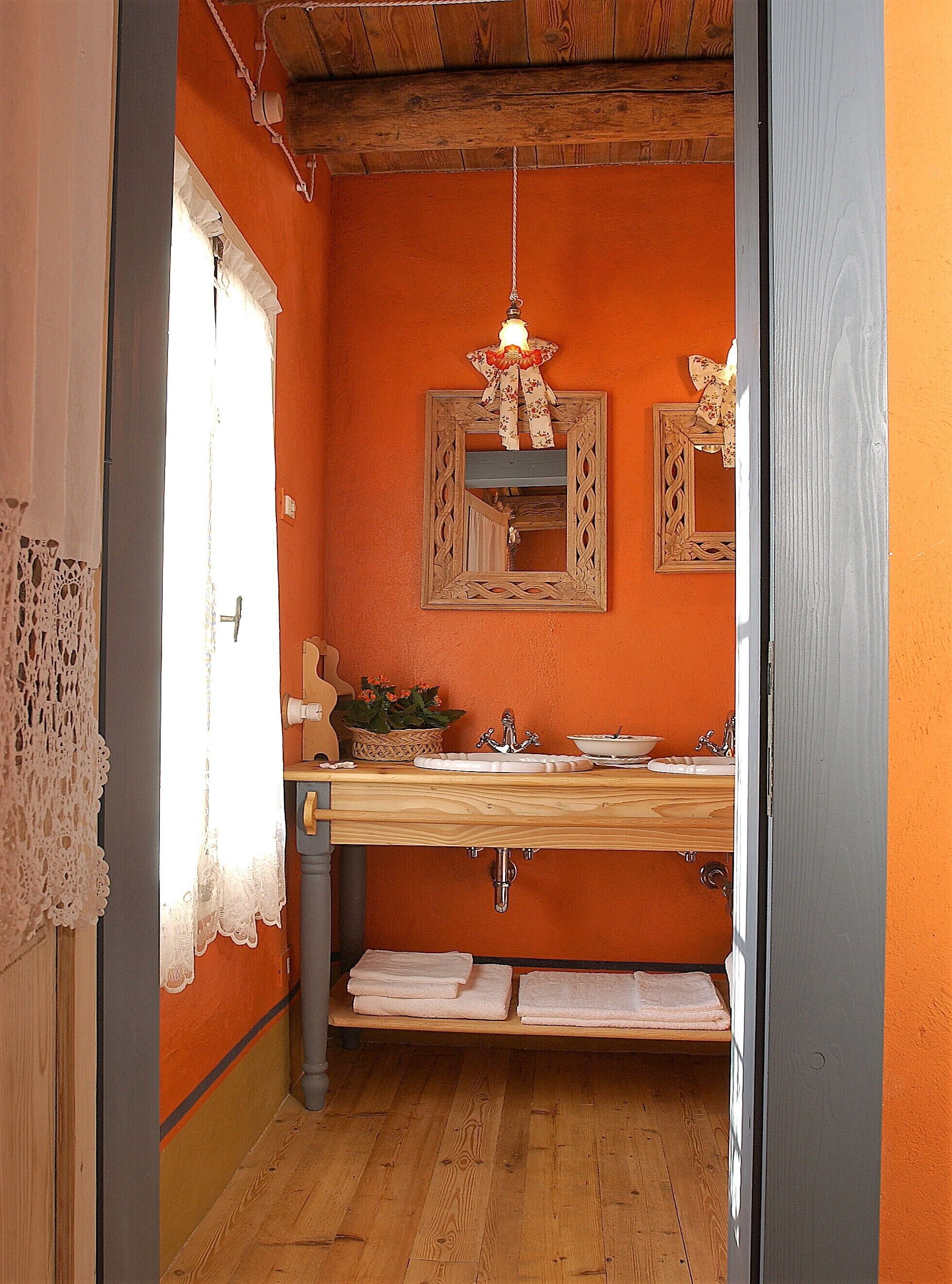 A bathroom with wooden flooring, a sink with a mirror, and a hanging light fixture.