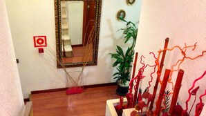 Una escalera con alfombra roja estampada, un espejo y plantas decorativas.