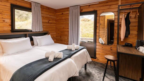 Una habitación de cabaña de madera con cama, escritorio y espejo.