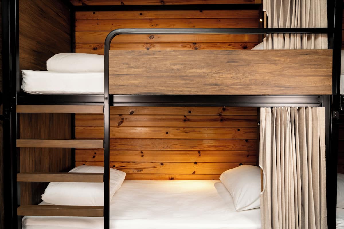 A bunk bed with wooden paneling and a curtain on the right side.